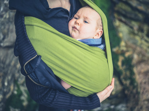 Young mother with baby in sling outdoors