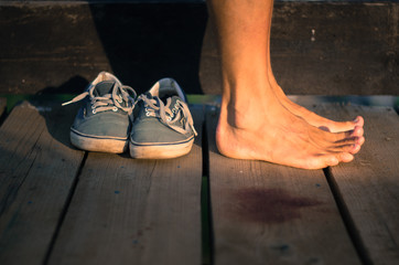 Old man's sneakers around with naked male legs on a wooden background