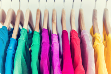 Fashion clothes on clothing rack closet. Closeup of colorful outfits on hangers in store closet or...