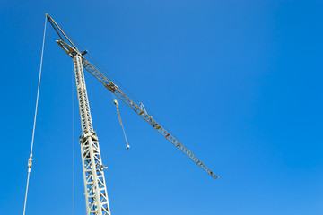 Crane at the construction site. Against the background of a blue clear sky.