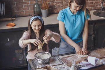 Young woman with her little sister cooking holiday pie