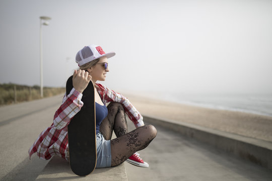 Fashion young woman posing with a skateboard