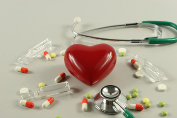 Pharmaceutical medicament, cure in container for health, stethoscope and heart on grey background.