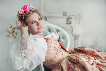 Beautiful woman in old-fashioned medieval dress on the sofa
