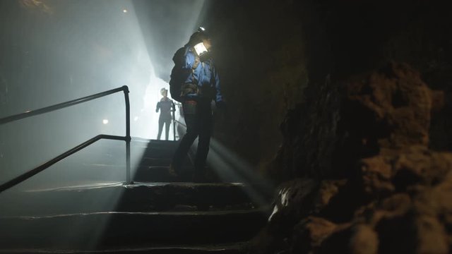  Potholers exploring cave system, shafts of light penetrating the dark