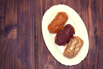 eclairs on white dish on wooden background