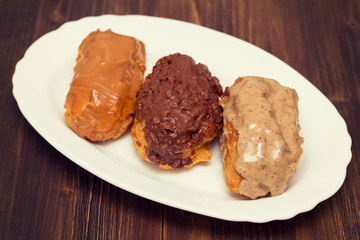 eclairs on white dish on wooden background
