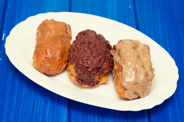 eclairs on white dish on wooden background