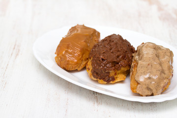 choclate eclairs on white dish on wooden background