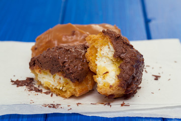 choclate eclairs on white paper on wooden background