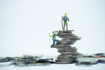 Miniature climbers team climbing on stack of coins. Business finance, challenging, compitition concept.