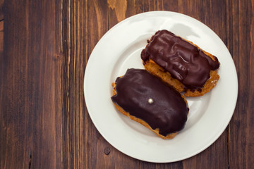 eclairs on white dish on wooden background
