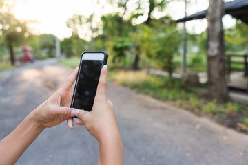 A male(man) hand hold(touch) and looking at smart phone  against sunset