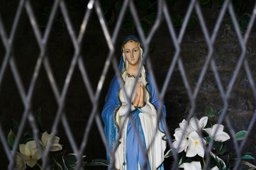 Statuette of Virgin Mary is hidden behind the bars. Metaphor - Negative attitude towards biblical...