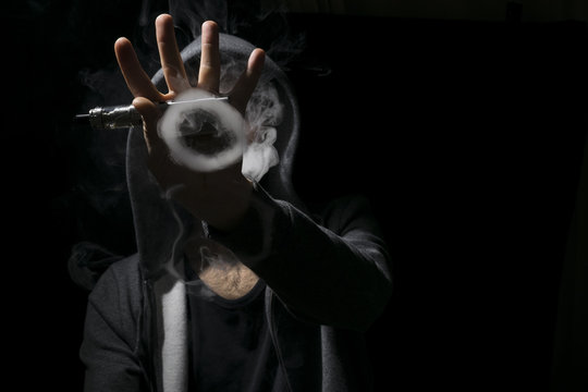 Circle tricks of smoke vaping by a young man.
