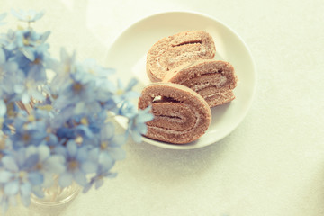 Delicious breakfast - biscuit roll on a background of sunny violets