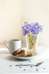 Delicious breakfast - biscuit roll with tea on a background of sunny violets