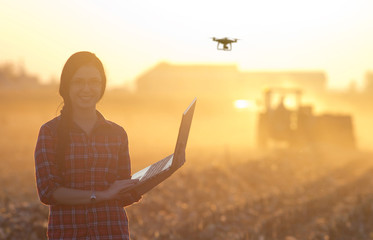 Woman with laptop and drone on field - obrazy, fototapety, plakaty