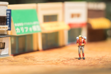 Miniature people with traveling concepts. Group of backpackers  walking by the travel attraction spot and shops. Concept of traveling or exploring the world, budget travel