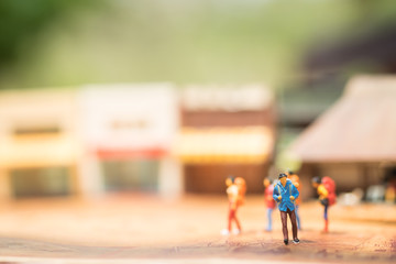 Miniature people with traveling concepts. Group of backpackers  walking by the travel attraction spot and shops. Concept of traveling or exploring the world, budget travel