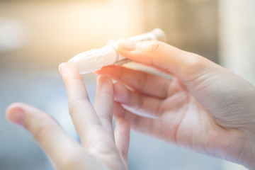 Close up of asian woman hands using lancet on finger to check blood sugar level by glucose meter, Healthcare medical and check up, diabetes, glycemia, and people concept