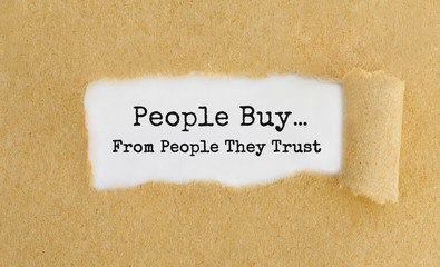 Text People Buy From People They Trust appearing behind ripped brown paper.