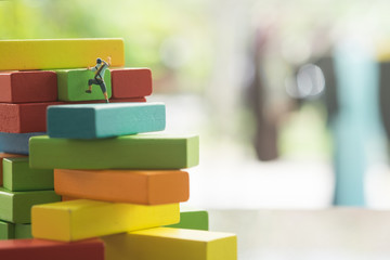 Miniature climbers team climbing on stack of colorful wooden blocks. Business finance, challenging, compitition concept.