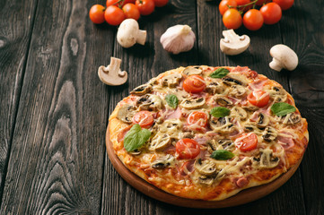 Homemade pizza with ham,mushrooms, tomatoes and cheese.