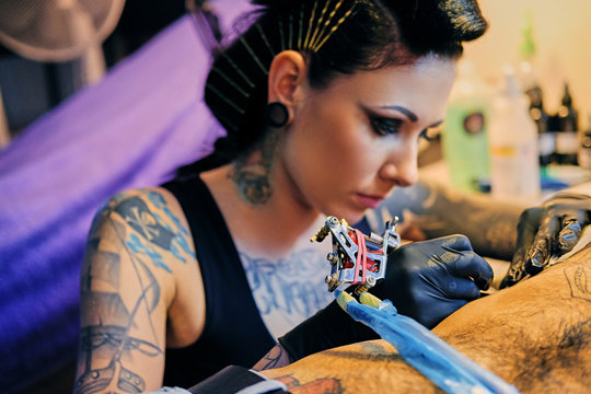 Close Up Image Of Female Tattoo Artist Makes A Tattoo On A Man's Torso.