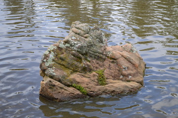 a large rock sitting in a pond