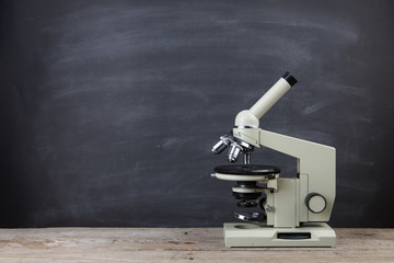 Science concept microscope on the table in the auditorium, blackboard background