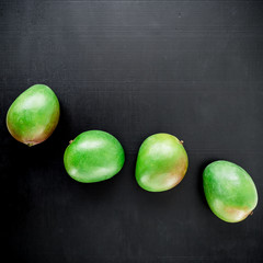 Tropical summer background. Mango on black background. Flat lay, top view.