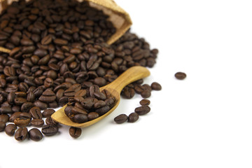 Coffee beans on a wooden spoon on white background
