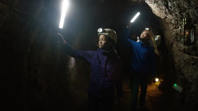  Female geologist exploring underground cave, looking at rock formation. 