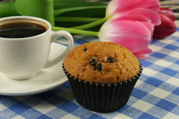Chocolate muffins with a Cup of coffee and flowers on the table
