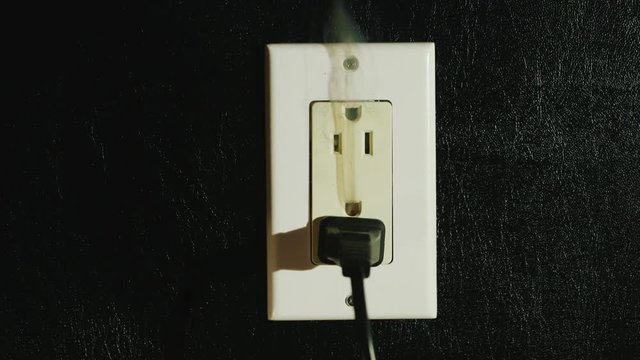 Fire in a dual-socket US type. Streams of black smoke come from the outlet. Danger to life and health