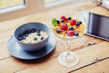 Golden corn flakes, Hercules oat and some berries in a cup on a wooden table.