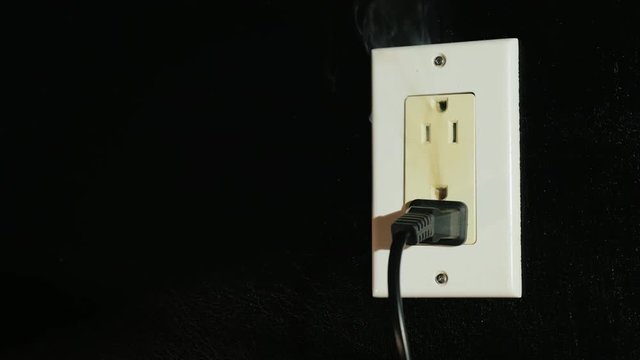 The beginning of the fire in an American type socket. Smoke streams come from a double home outlet - short circuit and fire