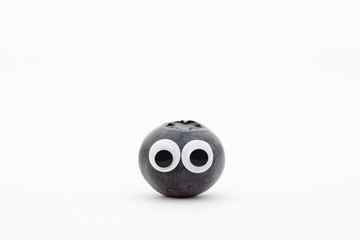 blueberry with googly eyes on white background