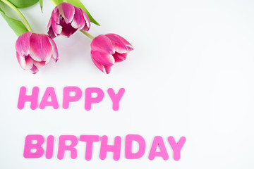 Die englischen Worte Happy Birthday in pink farbenen Buchstaben mit Tulpen isoliert auf weiß