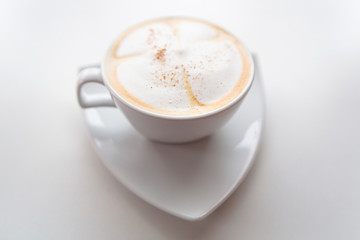 Cappuccino in a white cup on a white saucer.