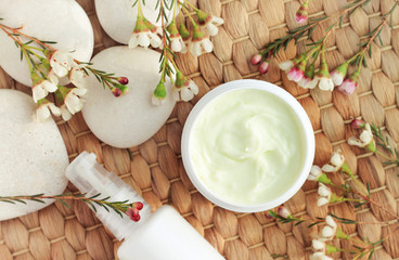 Cosmetic jar of skin care cream, blossom decor and stones, natural materials. Botanical spa treatment. 