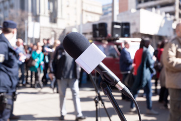 Fototapeta premium Protest. Demonstration. Microphone in focus, blurred protesters in background.