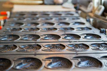 Fototapeta premium Multiple empty Taiyaki molds on a stove at a shop. Kyushu, Japan. Travel and cuisine concept.