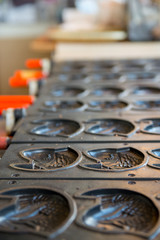 Close-up detail of multiple empty Taiyaki molds on a stove at a shop. Vertical orientation. Kyushu, Japan. Travel and cuisine concept.