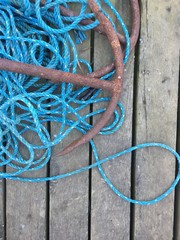 rostiger Anker mit blauem seil auf Holzsteg