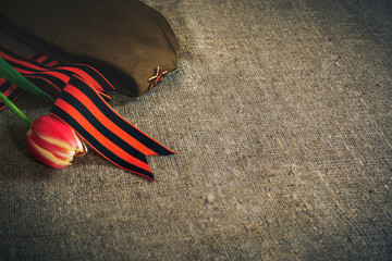 Military cap with order of Great Patriotic war and tulips flowers tied by Saint George ribbon