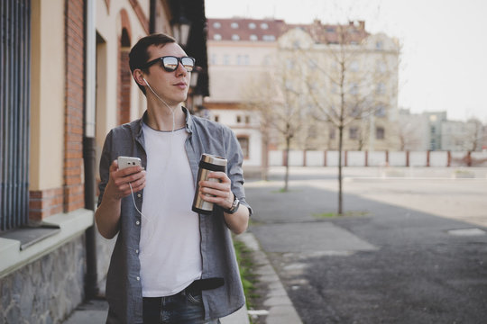 Young hipster man walking on the street and using his smartphone
