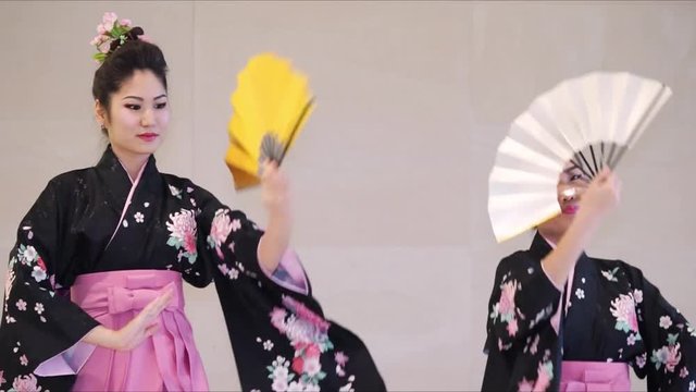 Two geisha in traditional japanese kimono with fans