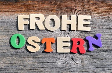 Frohe Ostern auf Holzhintergrund mit Osterglocken und bunten Blumen dekoriert